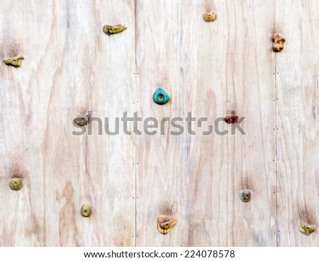 The wood surface of an artificial rock climbing wall with hand and toe hold studs, adventure and extreme sport activity.