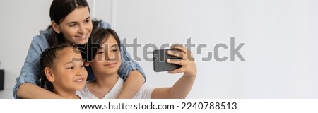 Asian boy taking selfie with sister and mom at home, banner