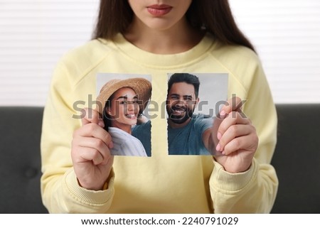 Woman holding torn photo indoors, closeup. Divorce concept