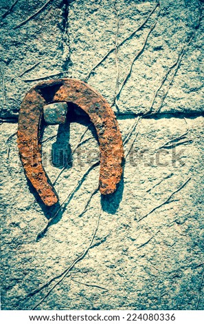 Old rusty horseshoe hanging on the stone wall of farmhouse. Aged photo.