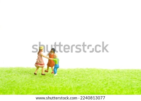 Miniature people toy figure photography. Playground arena concept. Kids playing together above green grass field. Isolated on white background. Image photo