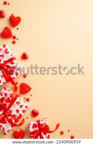 Valentine's Day concept. Top view vertical photo of gift boxes with ribbon bows heart shaped candies candles and sprinkles on isolated pastel beige background with copyspace