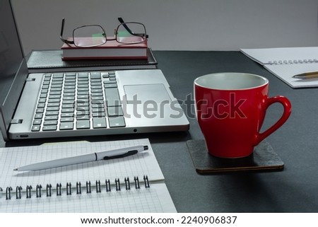 Laptop, notepads and a cup of coffee on the desktop
