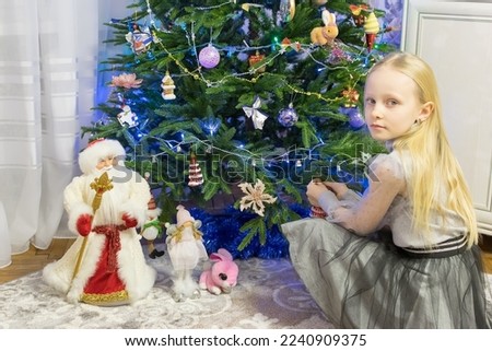 Girl with blond long hair decorates the Christmas tree
