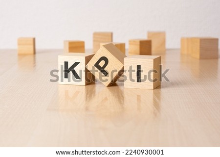 KPI - an abbreviation of wooden blocks with letters on a gray background. reflection caption on the mirrored surface of the table. selective focus