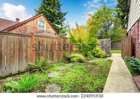 Concrete walkway leading to backyard area. HIgh wooden fence