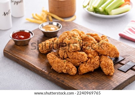 Fried chicken tenders or strips served with ketchup and fries Royalty-Free Stock Photo #2240969765