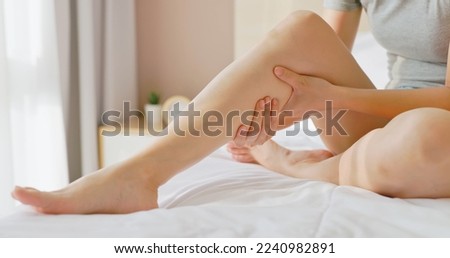 close up of asian woman hand touch massage her calf on bed in bedroom at home - she has leg cramp muscle pain Royalty-Free Stock Photo #2240982891