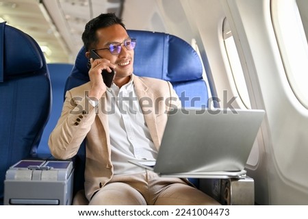 Successful and smart Asian businessman on the phone with his business client during the flight for an overseas business meeting. airplane, private jet, business class Royalty-Free Stock Photo #2241004473
