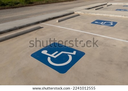 Group of empty disable person parking sign in public car park with worm sunlight. Wheelchair symbol with no people and blurred outdoors background. Selective focus and copy space.