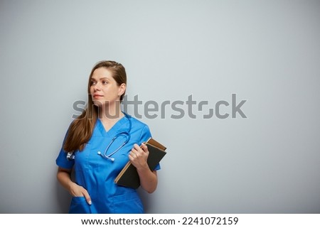 Serious doctor woman or nurse in blue medical suit with book. Isolated portrait of female medical worker.