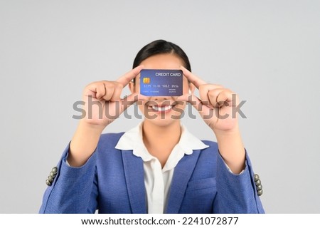 Selective focus, Asian young woman in officer uniform showing credit card in hand, standing posture with wireless earphone, isolated on white background