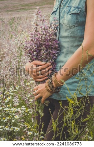 Lady with wind flowers bouquet in field scenic photography. Picture of person with fresh meadow on background. High quality wallpaper. Photo concept for ads, travel blog, magazine, article