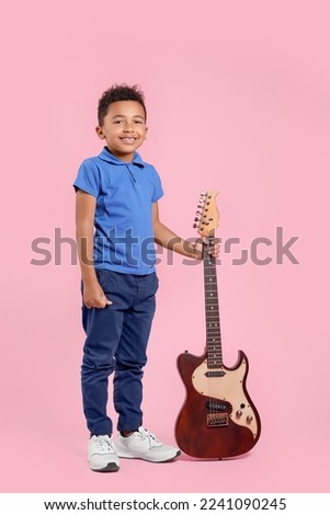 African-American boy with electric guitar on pink background