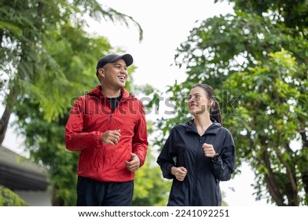 Couple jogging and running outdoors in nature. Happy Man woman wearing sportswear jogging in the Nature. Male and female in running uniform at outdoor. Workout exercise. Healthy and lifestyle. Royalty-Free Stock Photo #2241092251