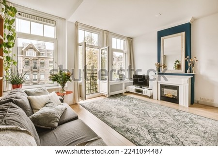 a living room with couches and a fireplace in the corner, surrounded by large windows that look out onto the street Royalty-Free Stock Photo #2241094487