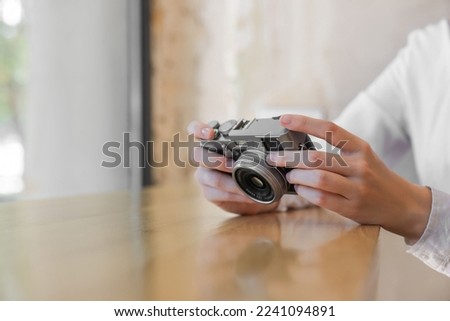Woman with camera at table indoors, closeup. Creative hobby