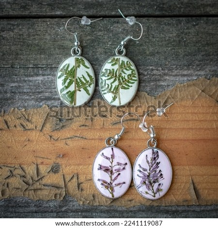 Close up craft earrings with lavender and fern concept photo. Top view photography with wooden table on background. High quality picture for wallpaper, travel blog, magazine, article