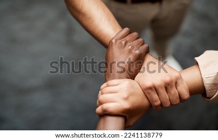 Hold onto your hunger for success. Shot of a group of businesspeople linking arms in solidarity in a modern office. Royalty-Free Stock Photo #2241138779