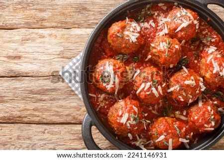 Fried meatballs with parmesan and then stewed in spicy tomato sauce close-up in a frying pan on the table. Horizontal top view from above
