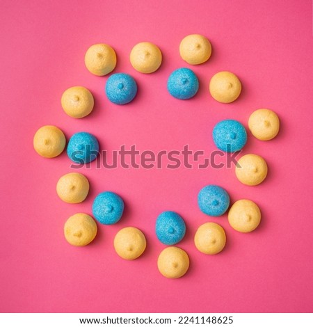 Optimistic round pattern of yellow and blue marshmallows on a pink background. Delicious holiday candies for parties and picnics. Abstract fun pattern with copy space, flat lay