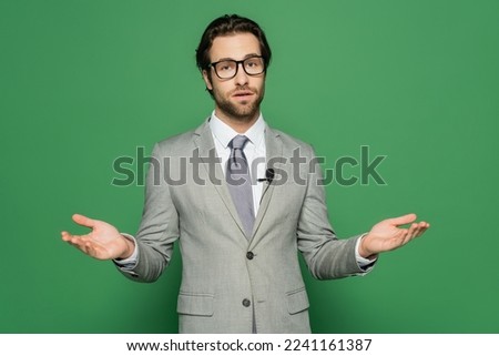 Newscaster in eyeglasses and clip microphone talking on green background