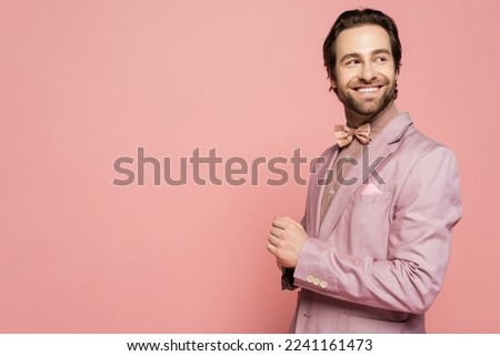 Positive host of event in jacket looking away isolated on pink with copy space