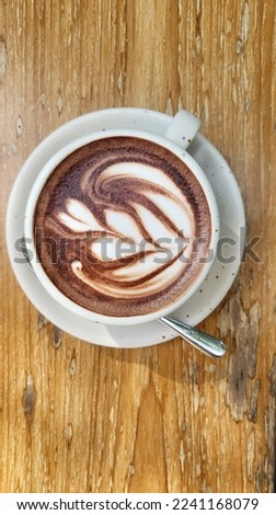 Cup of cappuccino with latte art on wooden background. Beautiful foam, greenery ceramic cups