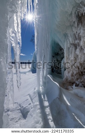 A sunstar winks through the opening of ice curtains as it shines through an ice cavern entrance on Lake Superiors Grand Island in Michigans Upper Peninsula