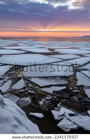 Sunrise lights up the sky above Lake Superior ice floes at the end of winter Royalty-Free Stock Photo #2241170337