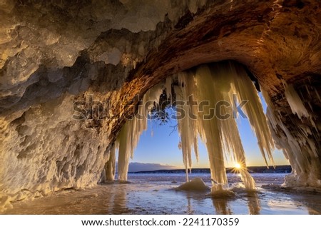 Icicles hang from the roof of an ice cave on Lake Superior during an extremely cold winter in Michigans Upper Peninsula. Ice curtains, created by a freeze-thaw cycle drape the entrance