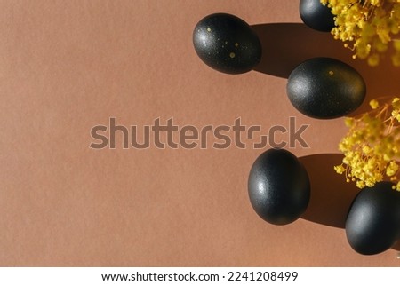 Eggs painted black on white background. Minimal Easter concept with copy space for text. Golden luxury backdrop