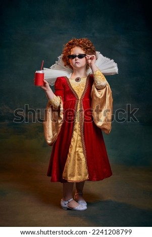 Portrait of little red-headed girl in costume of royal person posing in sunglasses and soda isolated on dark green background. Concept of historical remake, comparison of eras, medieval fashion, queen Royalty-Free Stock Photo #2241208799