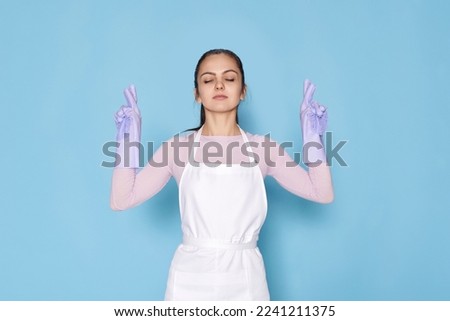 beautiful caucasian woman in gloves with finger crossed gesture
