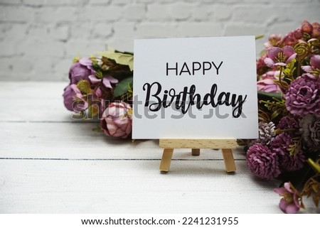 Happy birthday text on wooden easel standing on white brick wall and wooden background