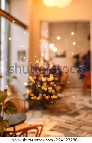 Close-up of Christmas tree with lights garland in modern coffee room with served table, festive decorated empty apartment cafe for New Year celebration, winter holiday concept. Selective focus. 