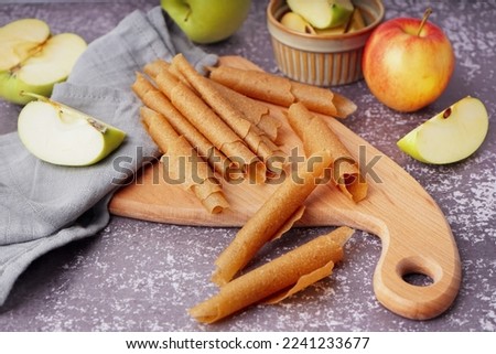 Wooden board with tasty apple pastilles on grunge background