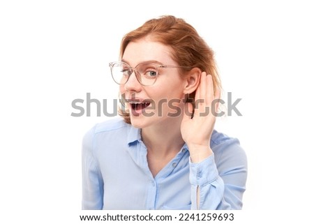 Young redhead woman in business shirt smiling and holding hand near ear, listening carefully, hearing intently isolated on white background Royalty-Free Stock Photo #2241259693