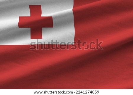 Tonga flag with big folds waving close up under the studio light indoors. The official symbols and colors in fabric banner Royalty-Free Stock Photo #2241274059
