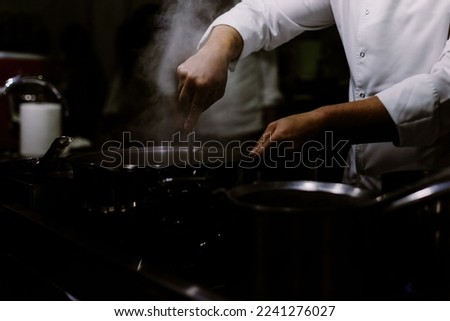 A cook stirring pots in the kitchen. Big pots in the kitchen.
BLURRY BACKROUND. BLURRED