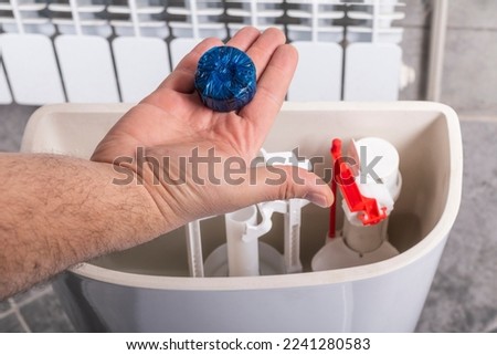 Studio lighting. bathroom. Toilet bowl. The housewife adds a special cleaning and disinfection agent to the barrels Royalty-Free Stock Photo #2241280583