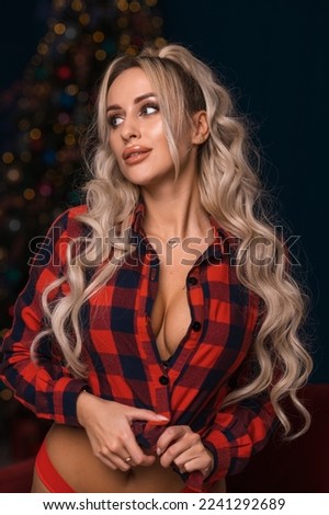 A bright blonde with long hair in a New Year's look near the Christmas tree