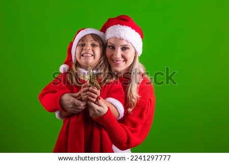 mother and daughter celebrating christmas on isolated background. Mother and daughter in christmas outfit holding golden star on green background