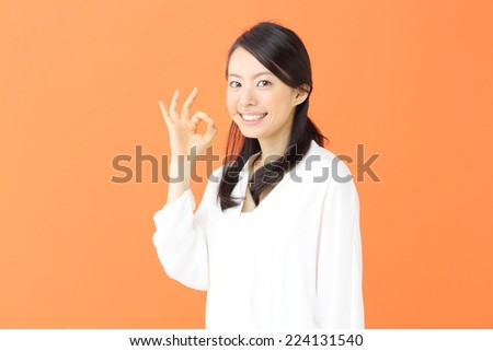 beautiful young girl showing OK sign against orange background