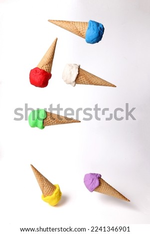 Fake modelling clay multi colourful ice cream on waffle biscuit cone drop fly fall on white background 
