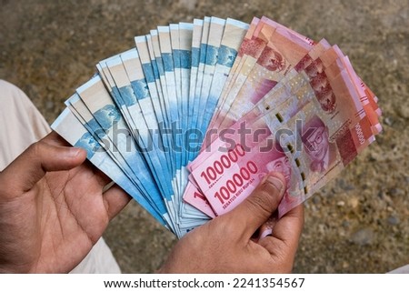 man showing Indonesian rupiah banknotes Royalty-Free Stock Photo #2241354567