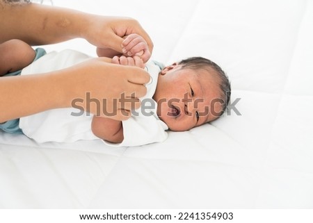 Hands of mother or nurse and newborn baby sleep on bed. Mom or nurse taking care newborn in the hospital