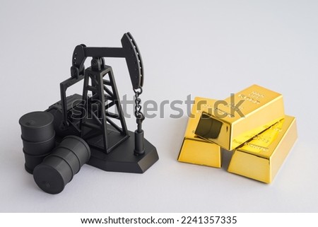 Crude oil tanks and pump jack vs gold bars on white background copy space. Commodity trading, investment, risk management, invest trategy plan, relationship between gold and oil price concept.