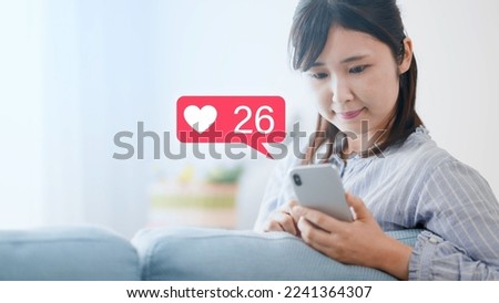 Young woman operating a smartphone on a sofa