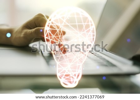 Creative light bulb hologram with hands typing on computer keyboard on background, idea concept. Multiexposure